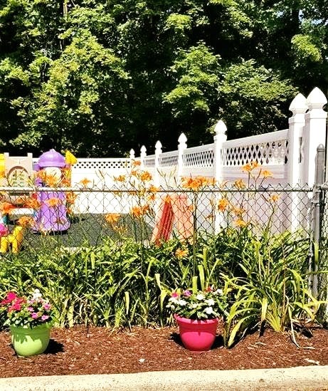 Playground with white fence and orange flowers