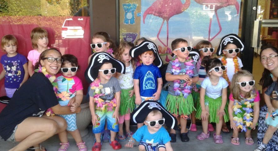 Adults and children in pirate hats, sunglasses, and hula skirts