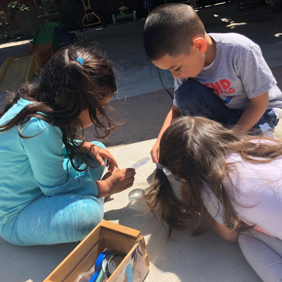 Three children looking at an object on the ground