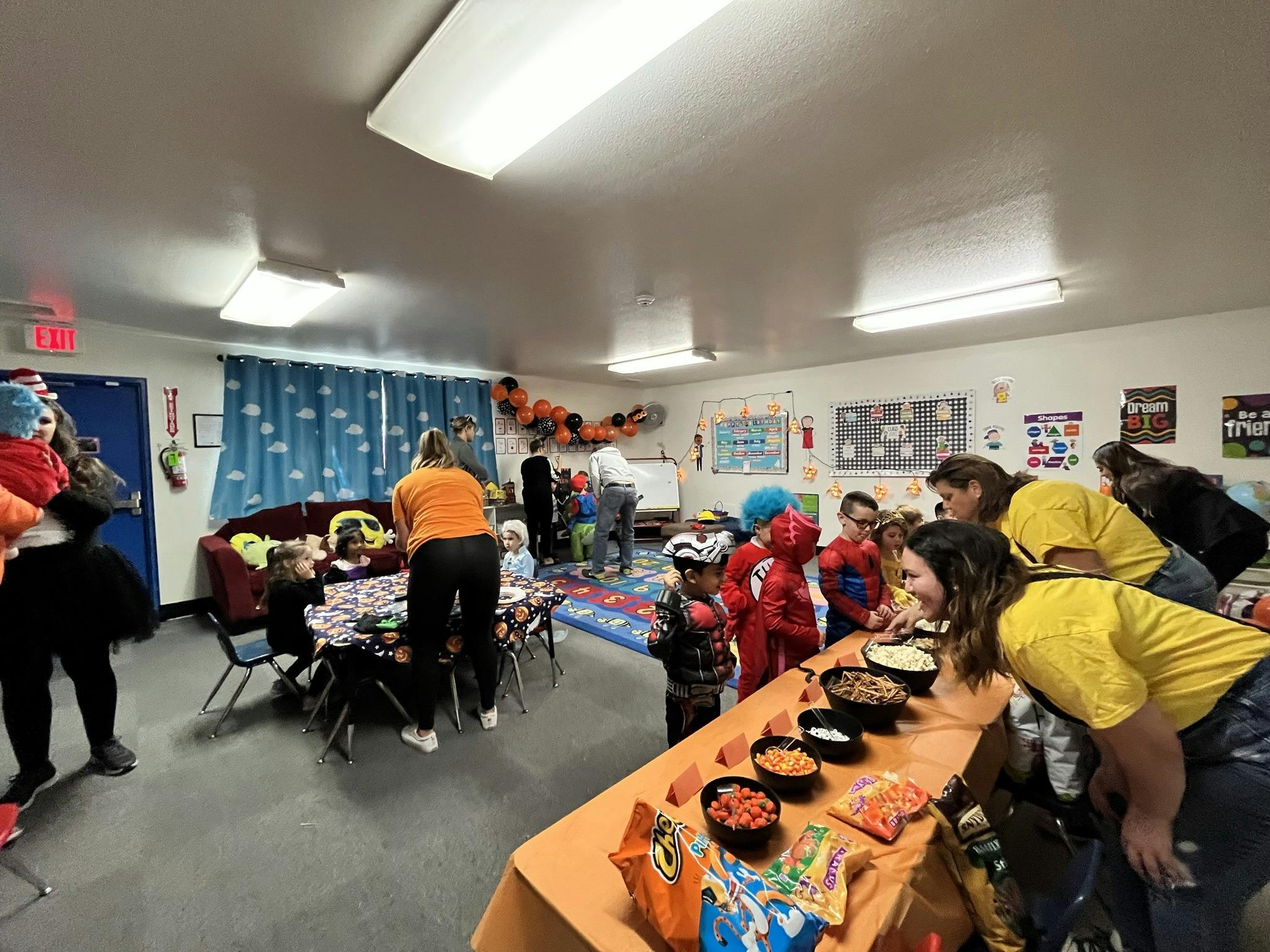 People and children in costumes gathered around tables with food
