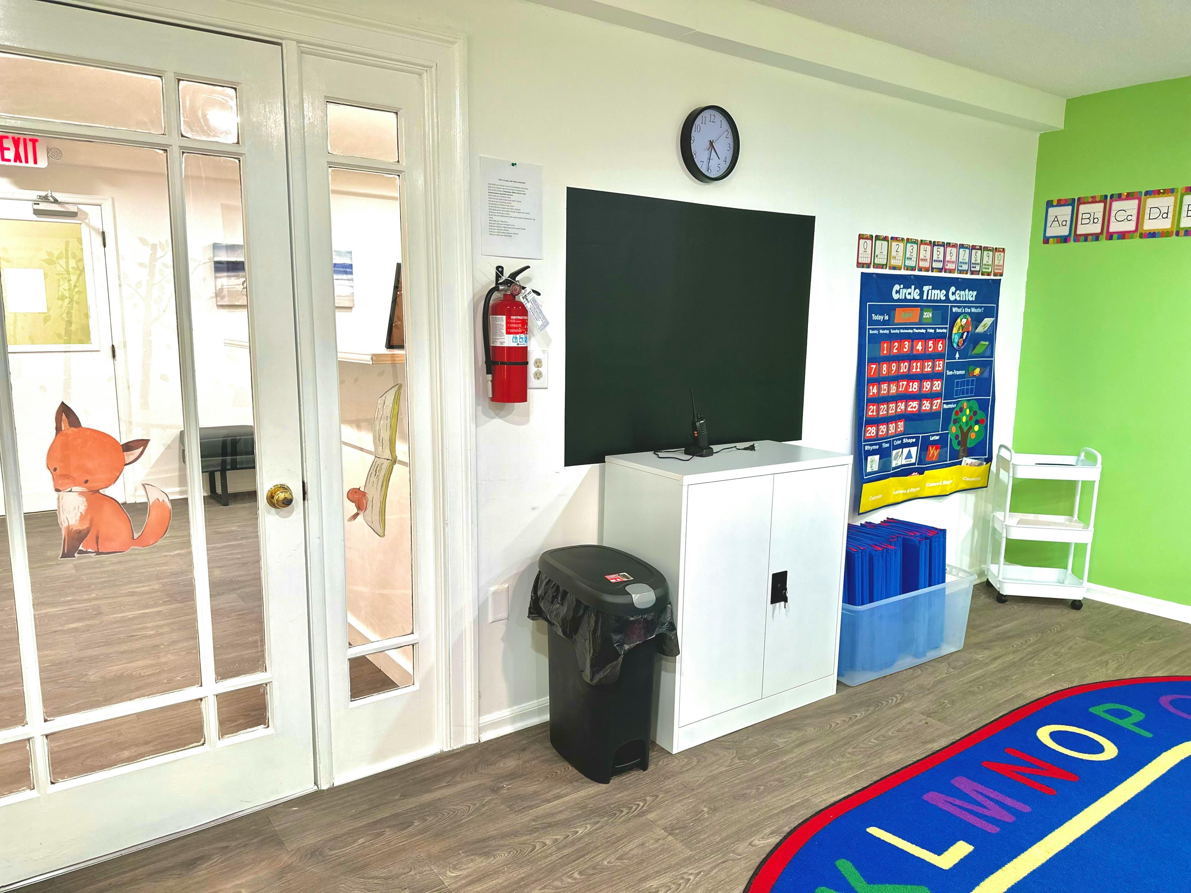 Classroom with a chalkboard, fire extinguisher, and alphabet rug