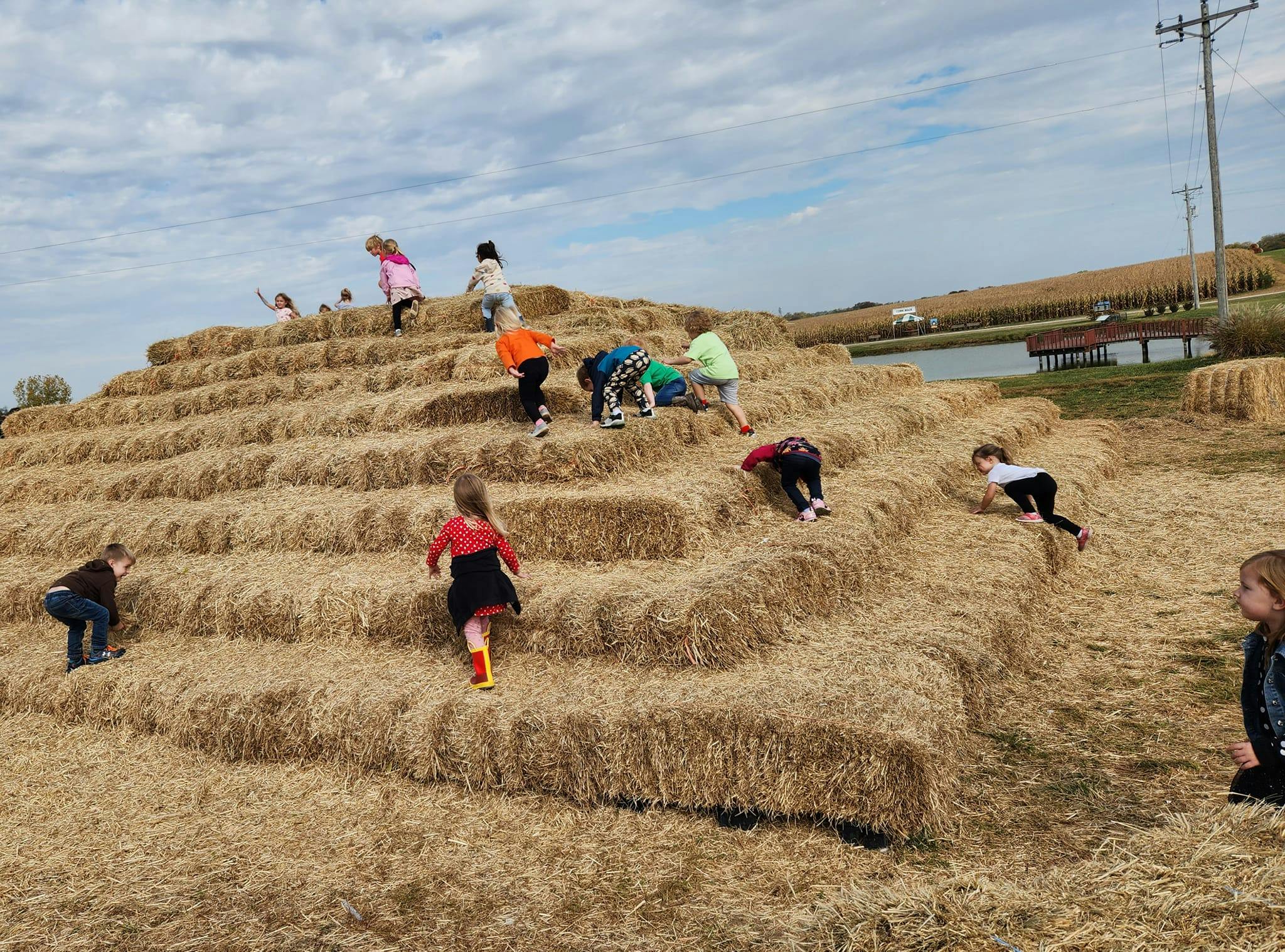 Children climbing on a large hay bale structure