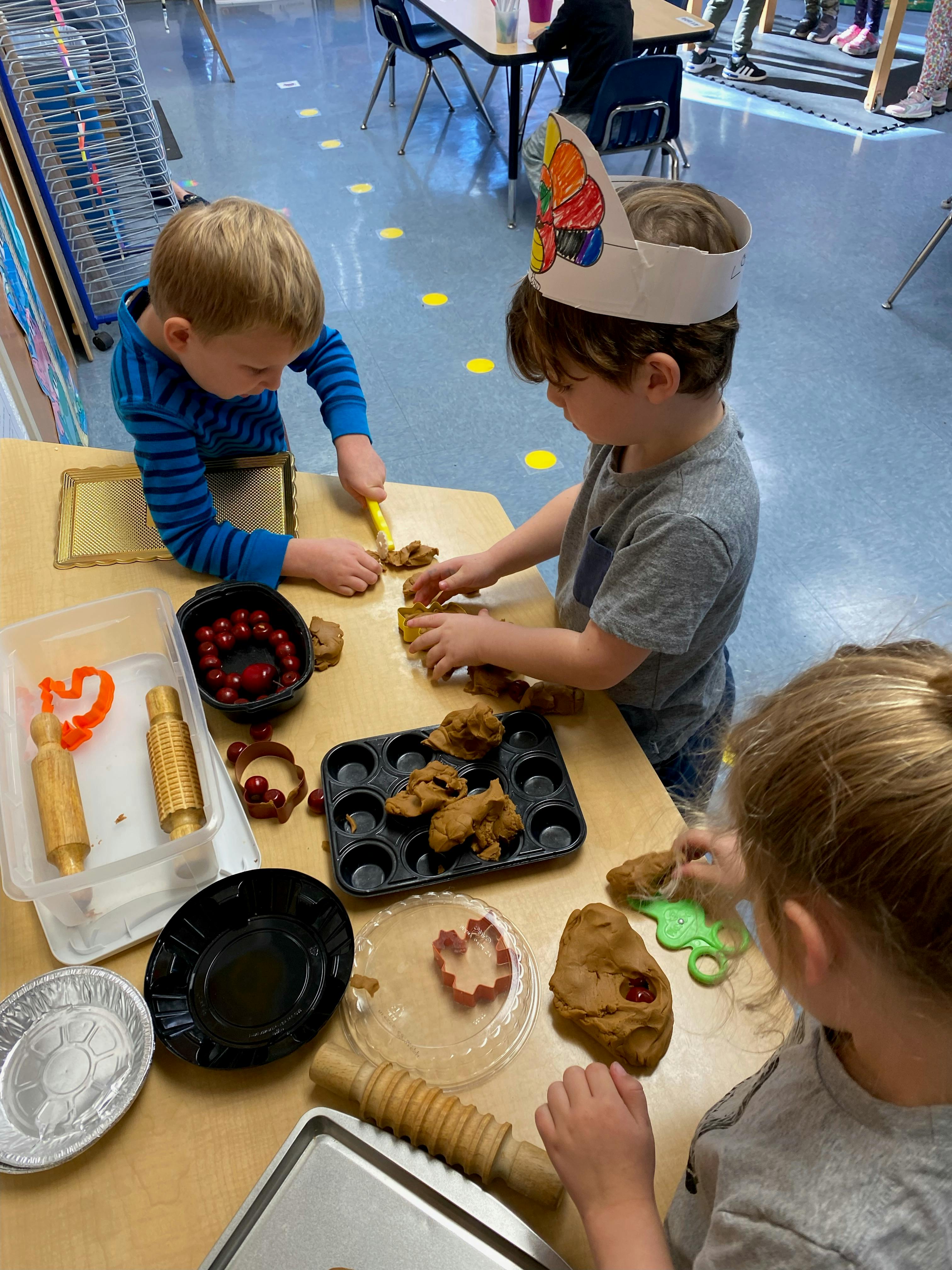 Children playing with dough and baking tools in a classroom