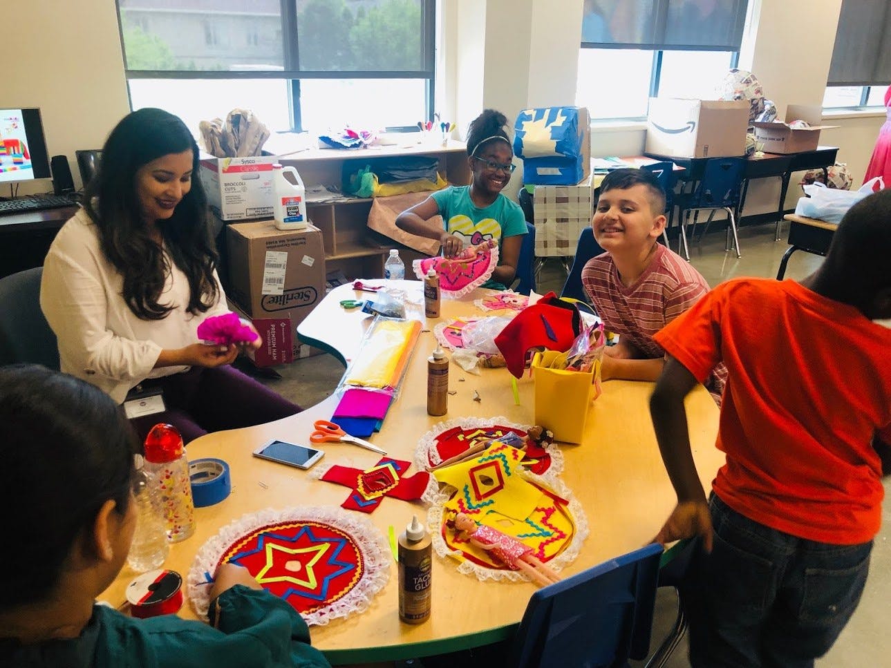 Adult and children doing crafts at a table in a classroom