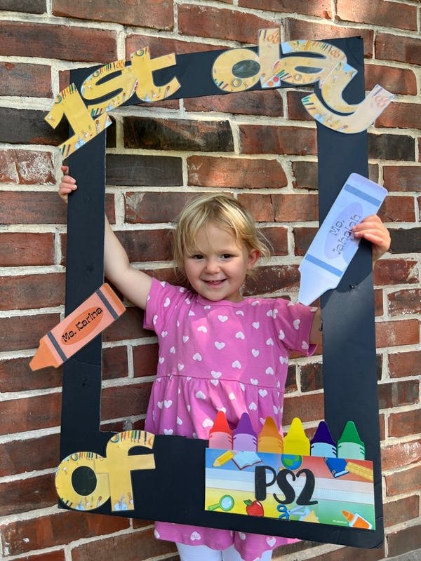 Child holding a 1st day of PS2 school frame