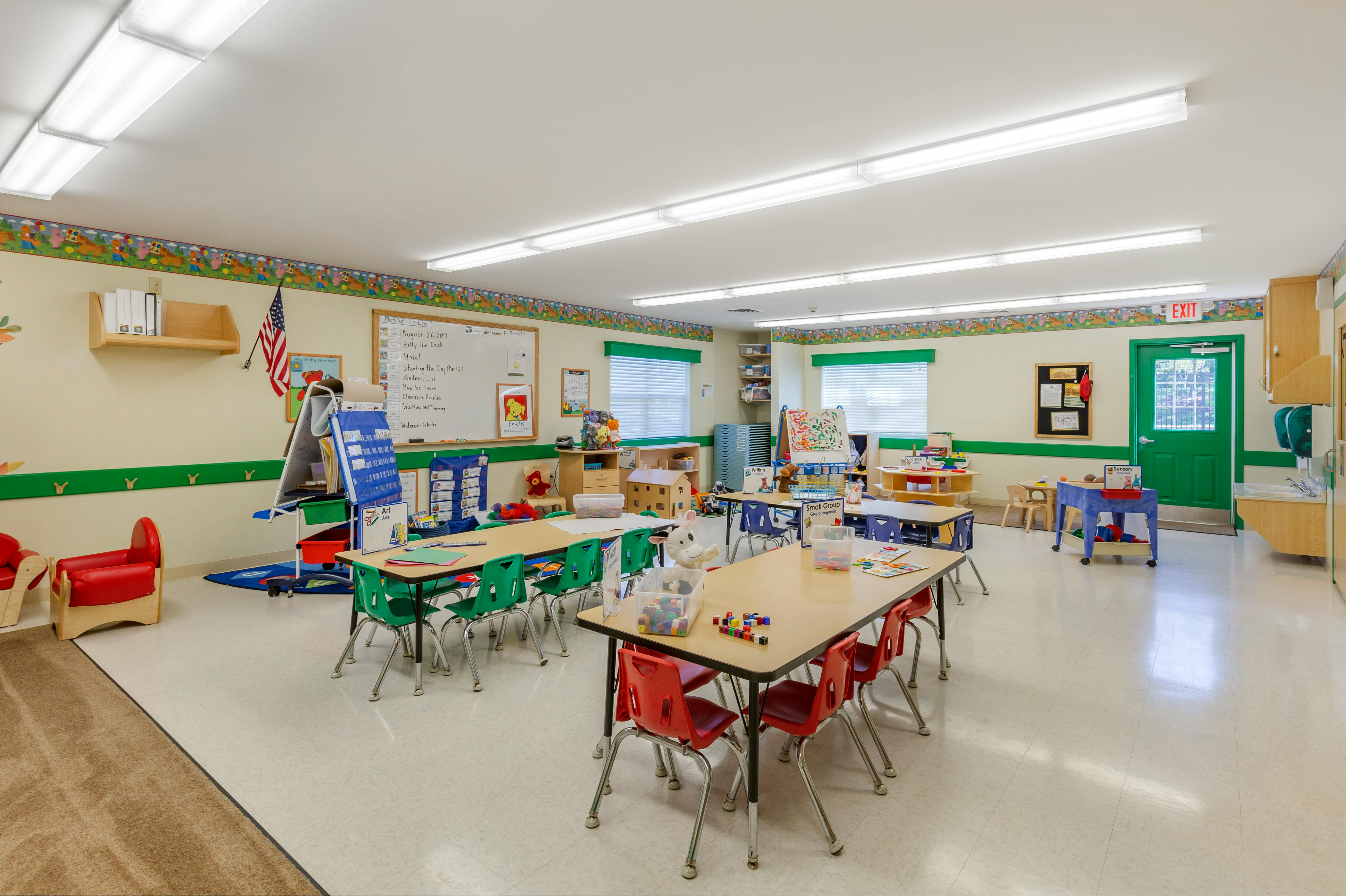 Classroom with child-sized tables and chairs, whiteboards, and windows