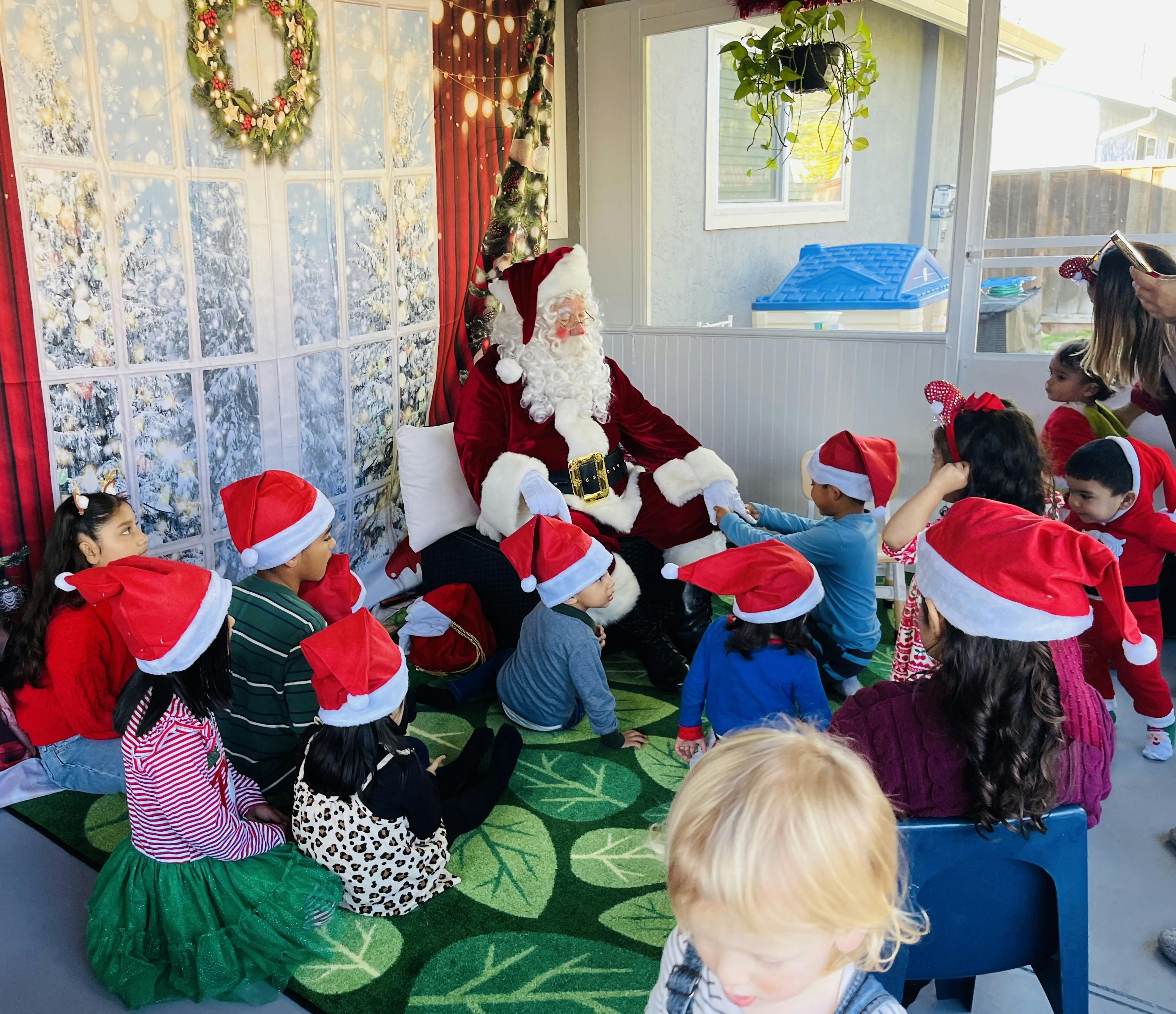 Group of children wearing Santa hats sitting around Santa Claus