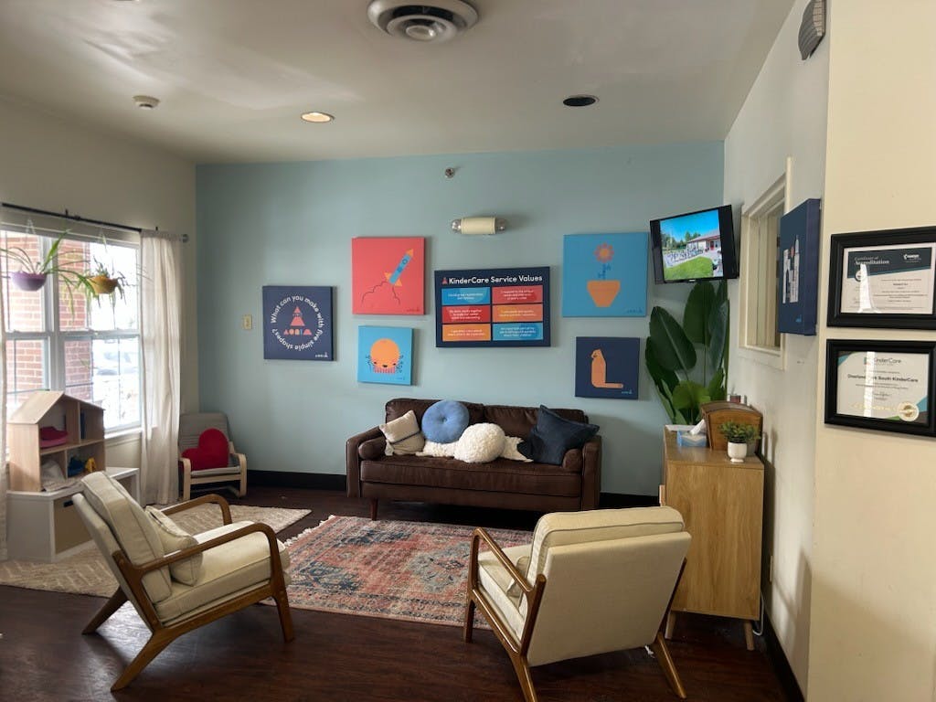 Lobby waiting area with a brown couch, two armchairs, and art on the wall