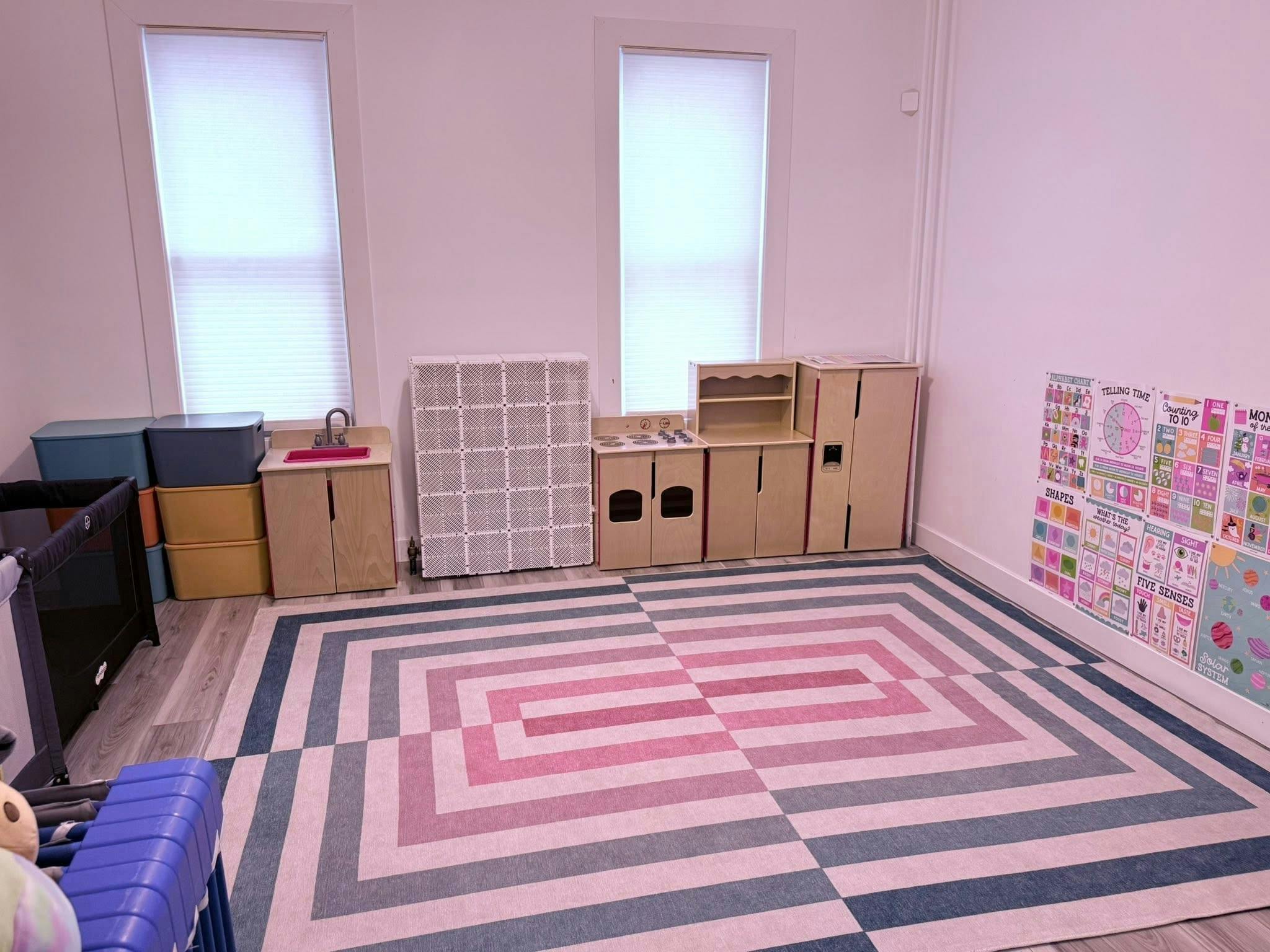 Playroom with toy kitchen and educational wall posters on a large geometric rug