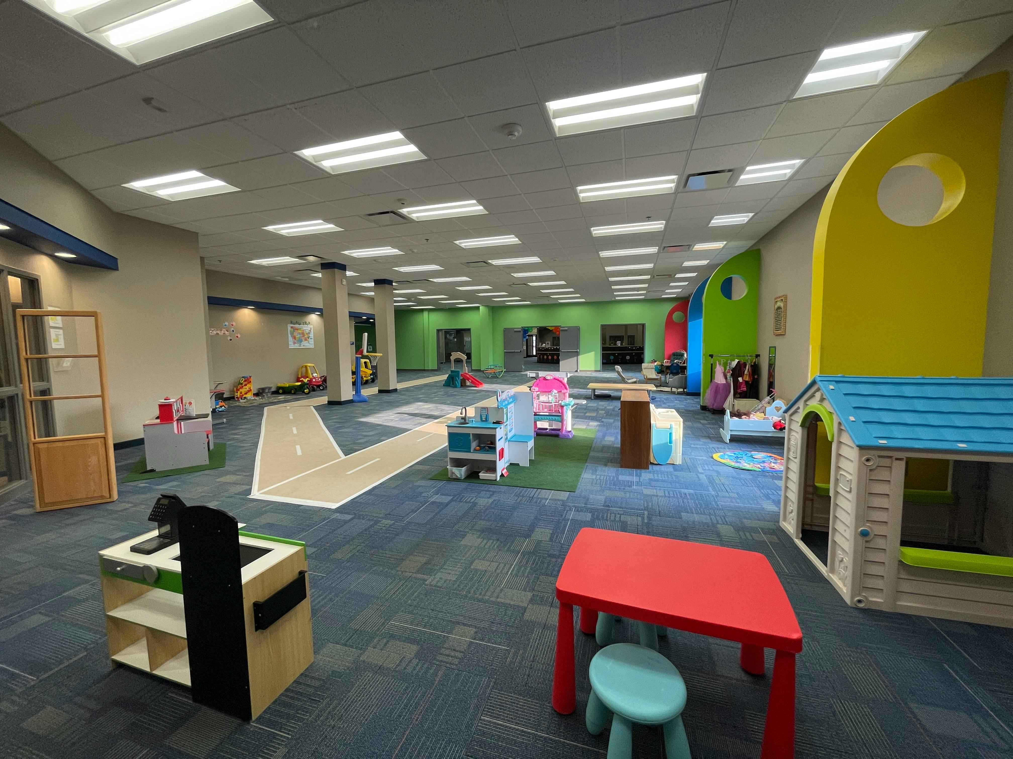 Indoor play area with small tables, chairs, and playhouses
