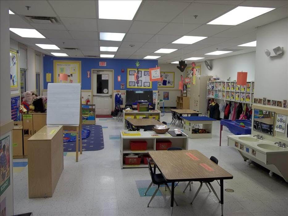 Empty classroom with small tables, chairs, and learning materials
