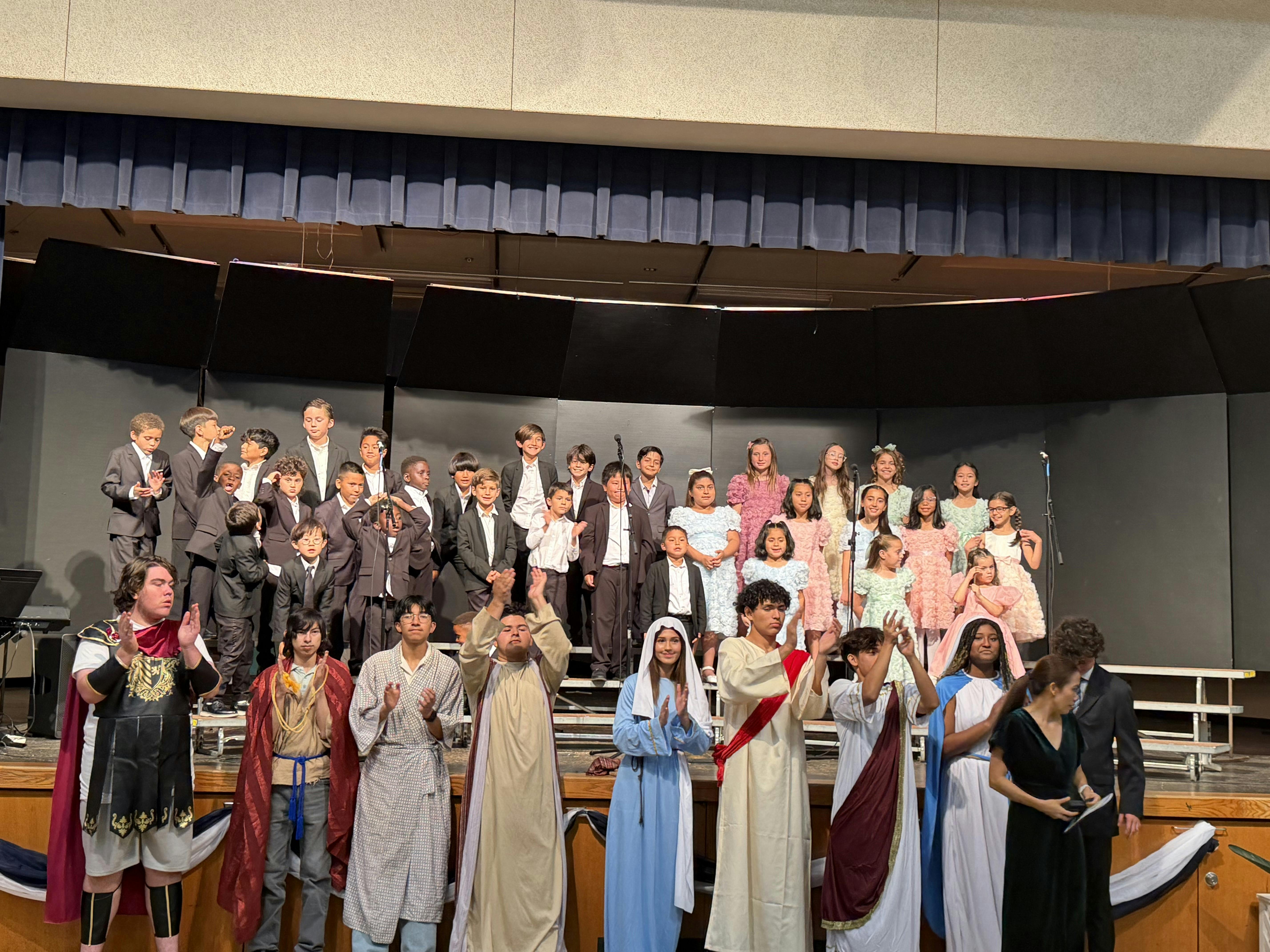 Group of children and teens in costumes standing on a school stage