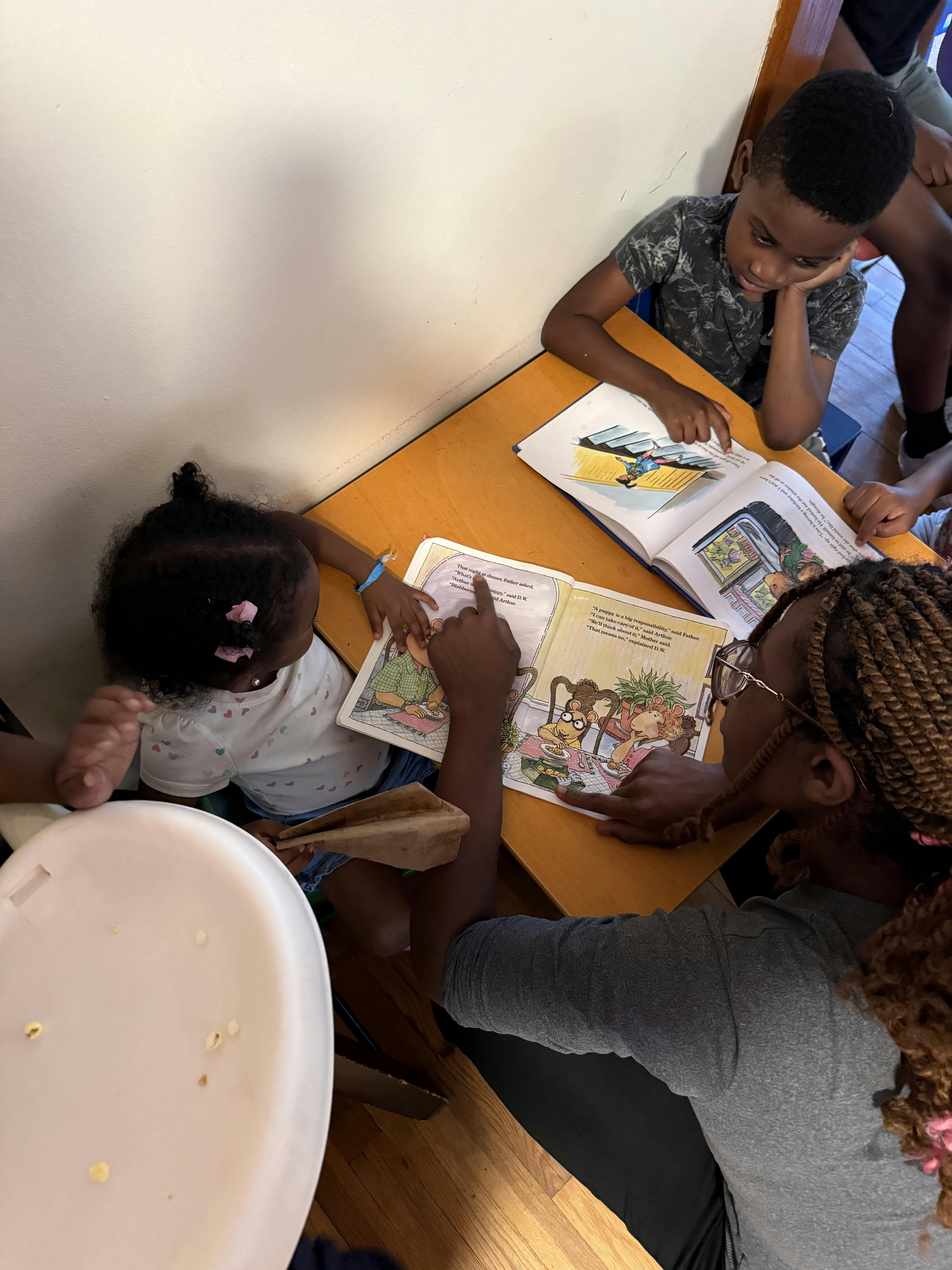Adult and two children reading books at a table