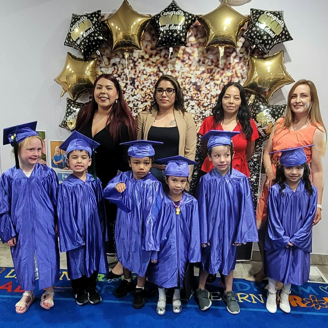 Group of adults and children in graduation caps and gowns