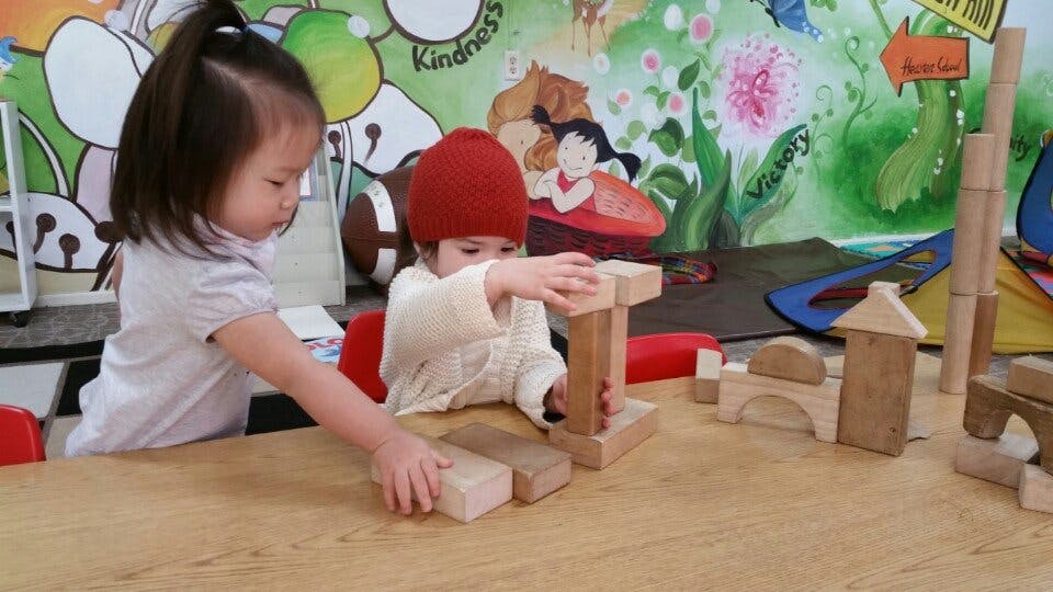 Two children playing with wooden blocks at a table