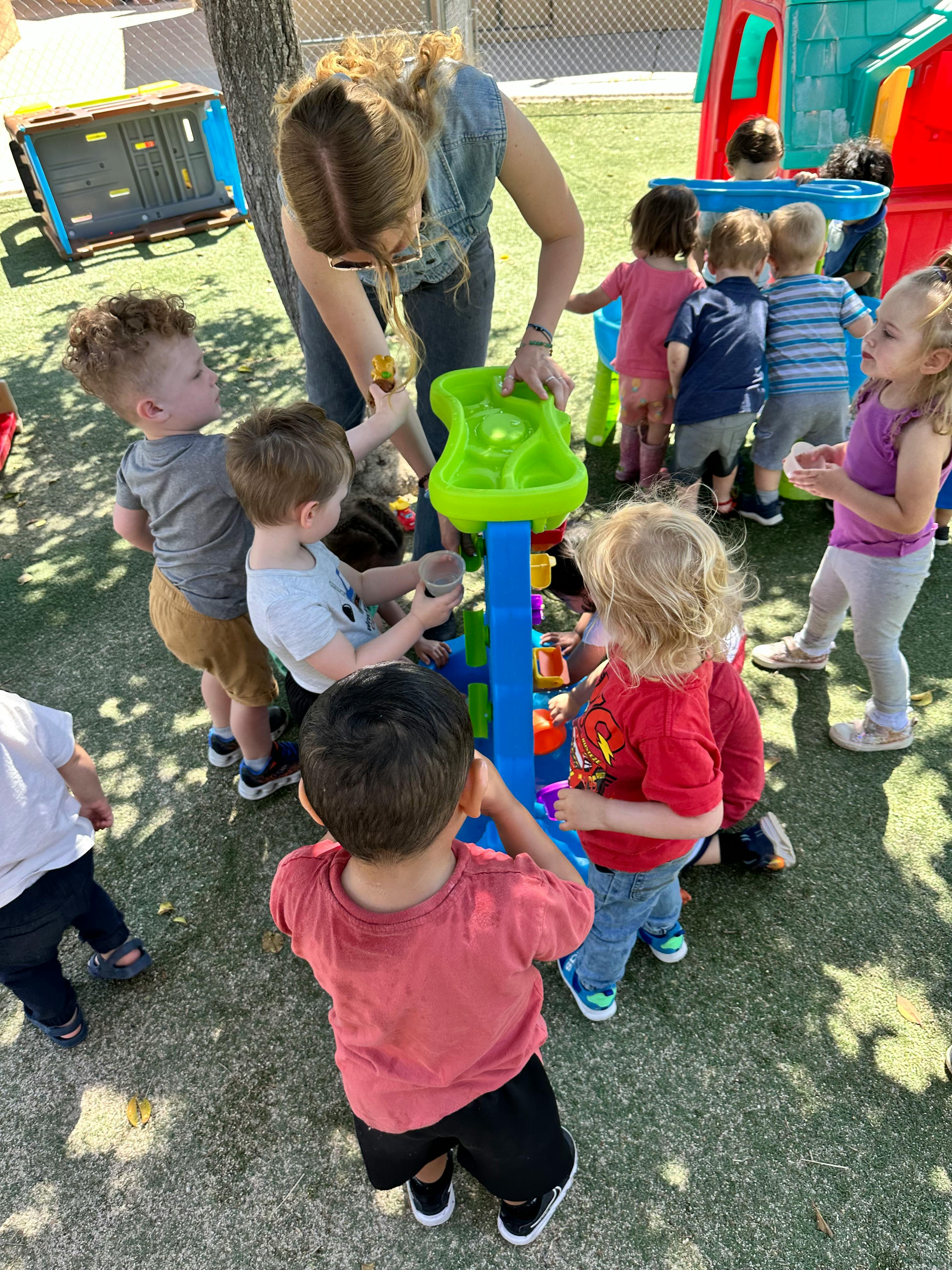 Adult and children playing with a water table outdoors