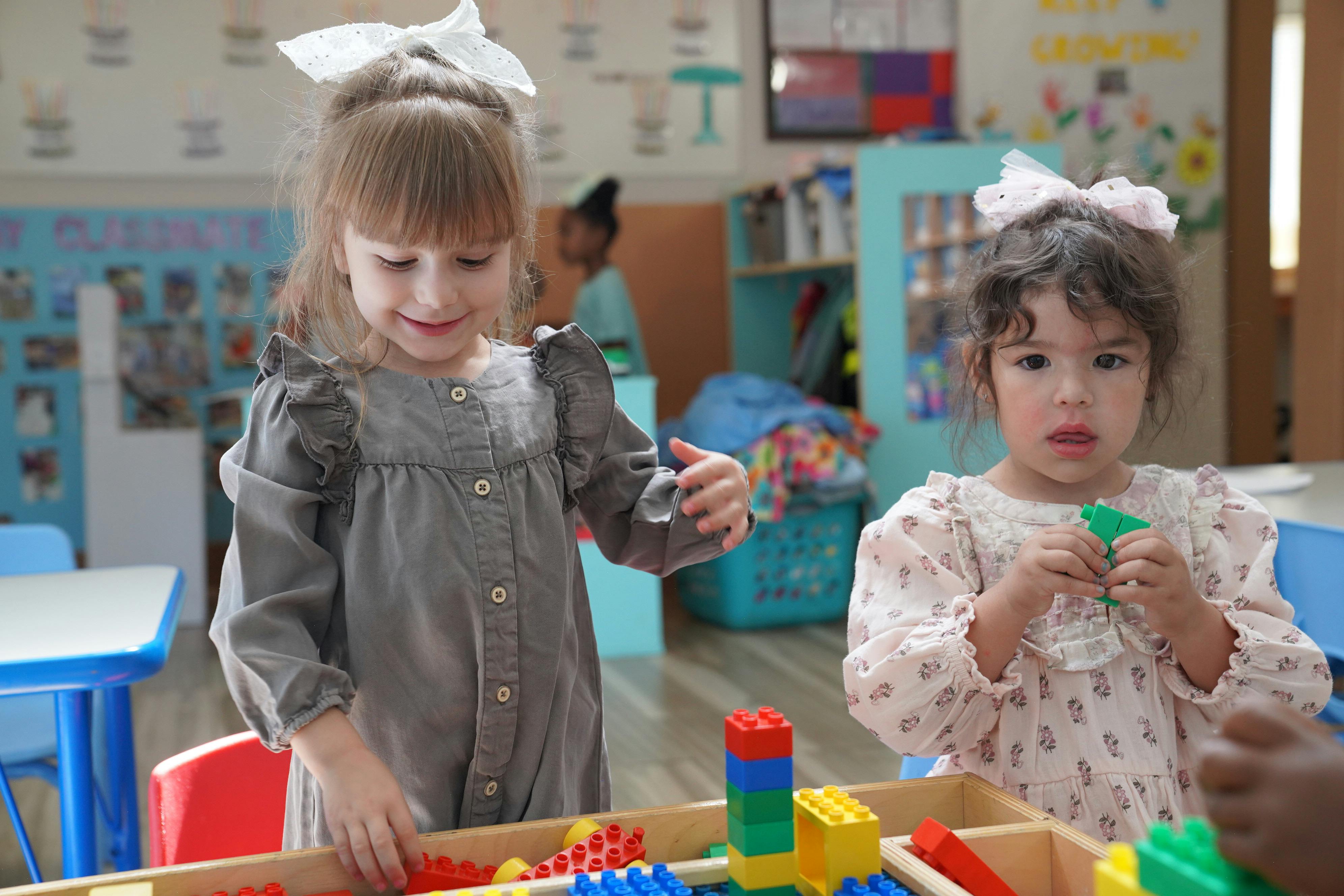 Two children playing with building blocks in a classroom