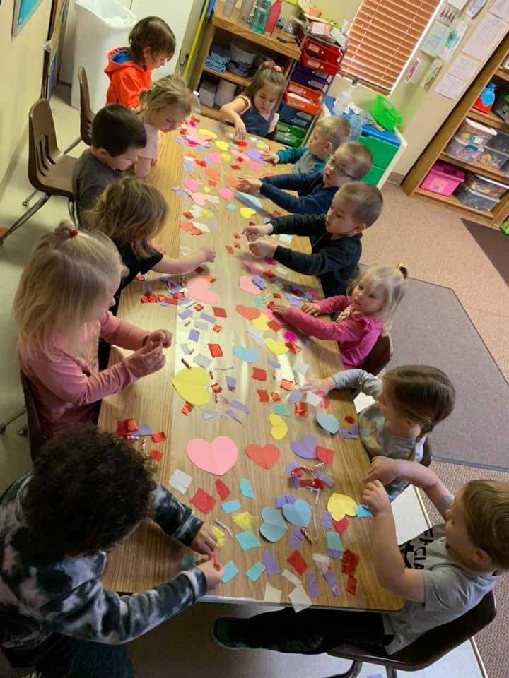 Children at a table doing crafts with paper shapes