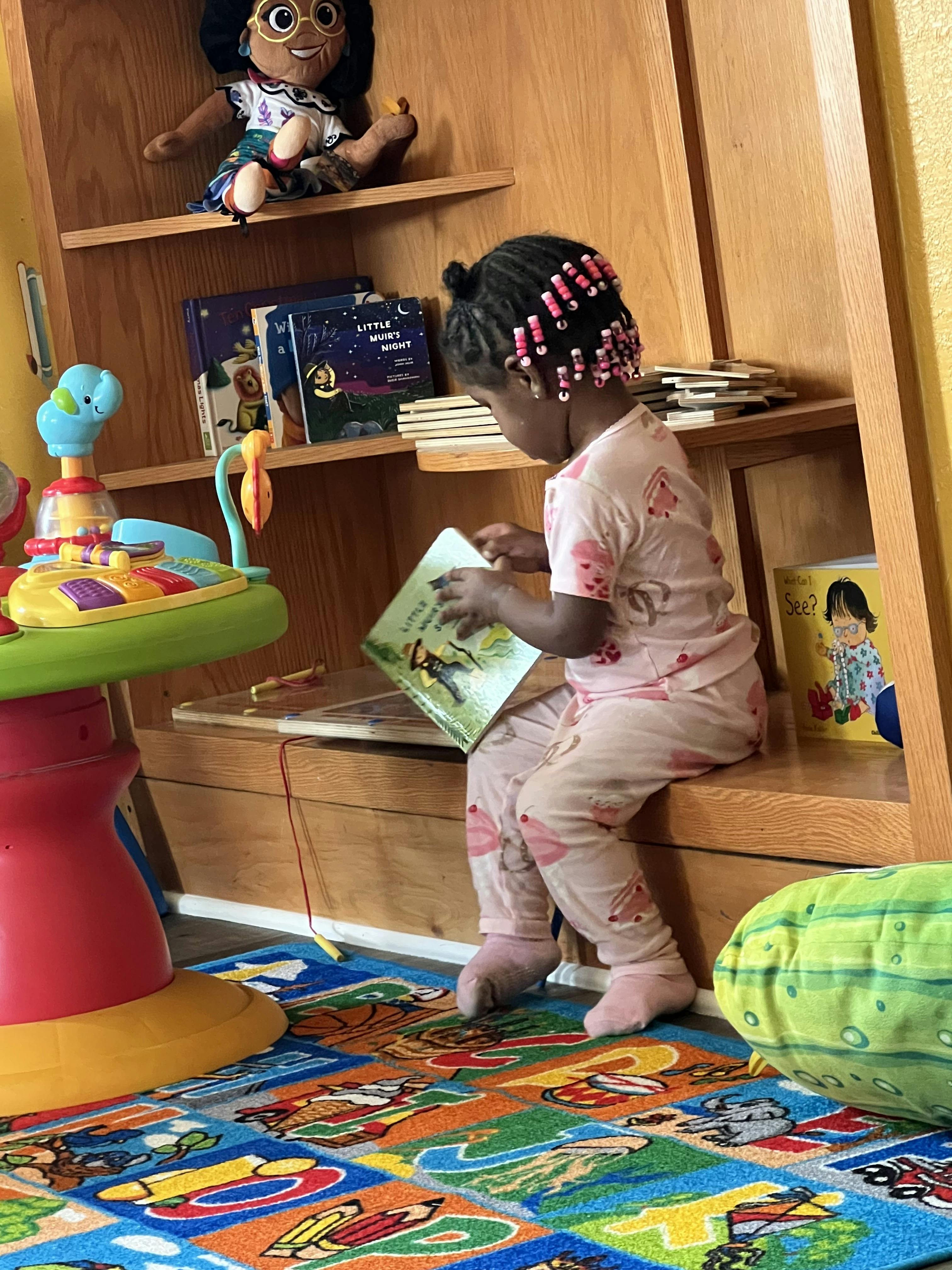 Child sitting on a shelf, reading a book