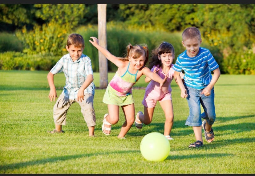 Four children playing with a ball on grass