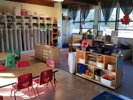 Classroom with tables, chairs, and shelves filled shelves