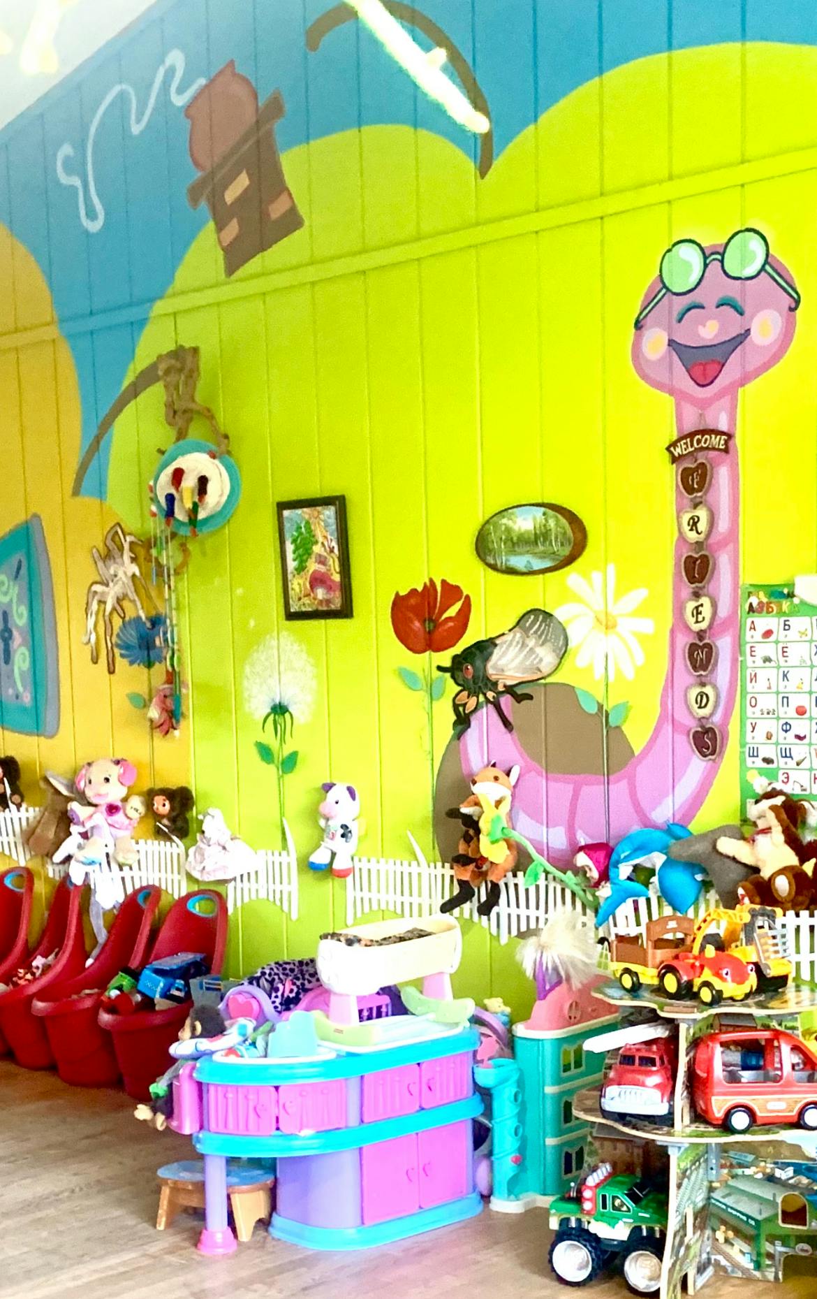 Playroom with toys and a wall mural featuring a snake holding a welcome sign