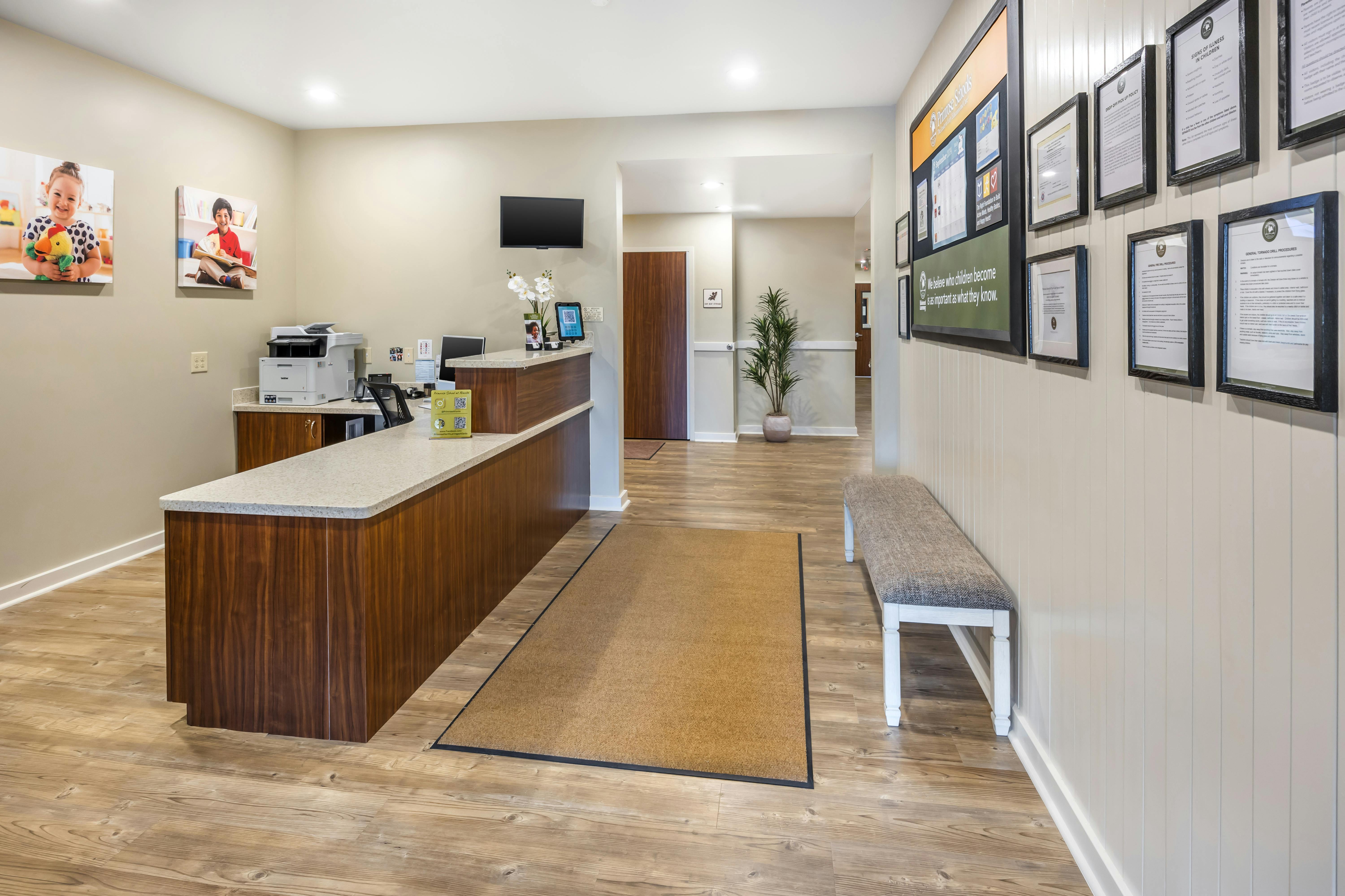 reception desk and waiting area with a bench and wall full of framed documents
