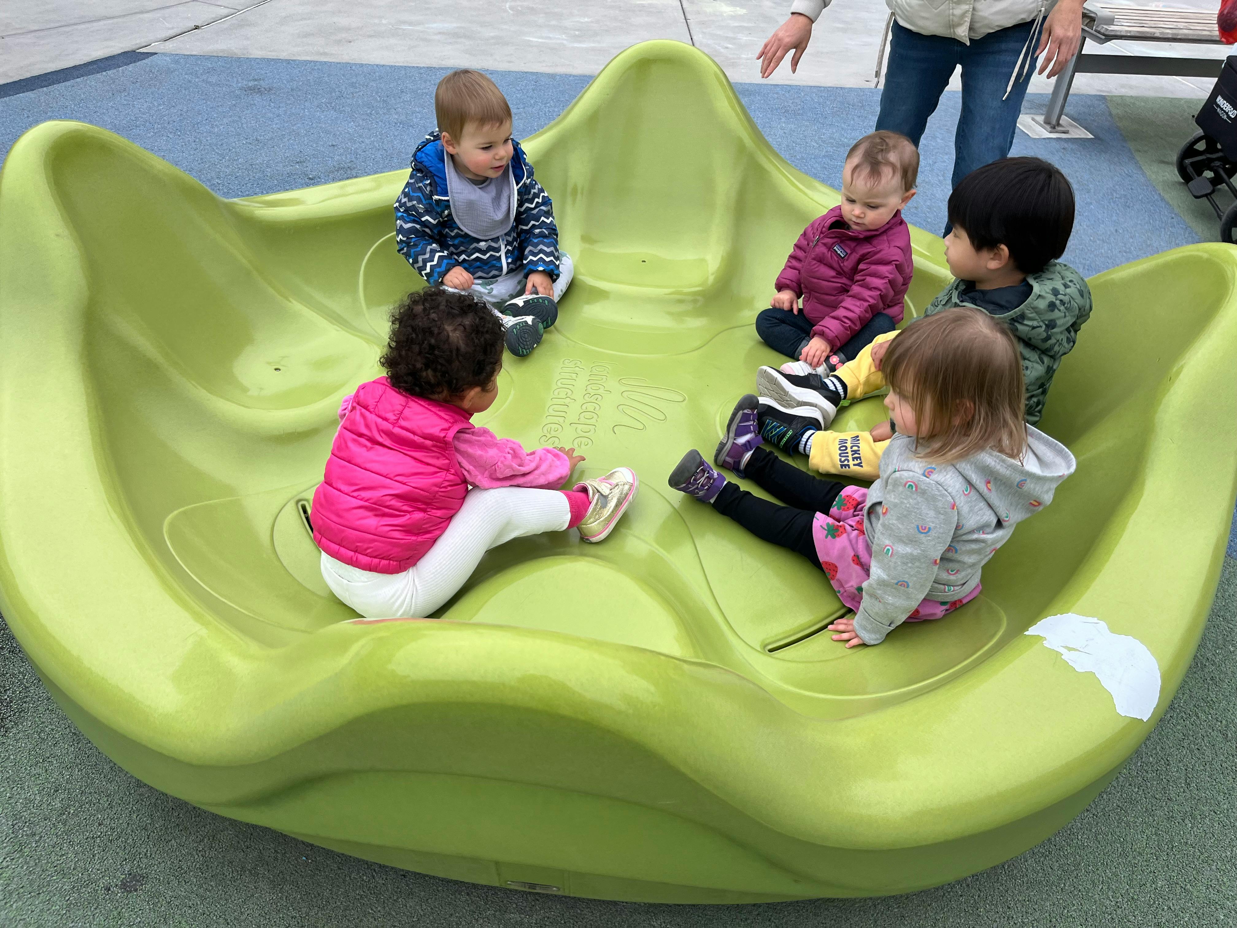 Multiple children sitting in a green play structure