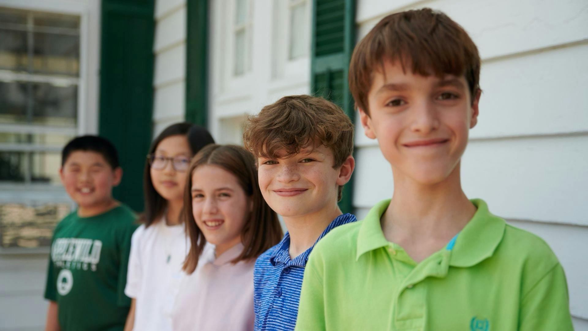 Five children standing in a line, smiling