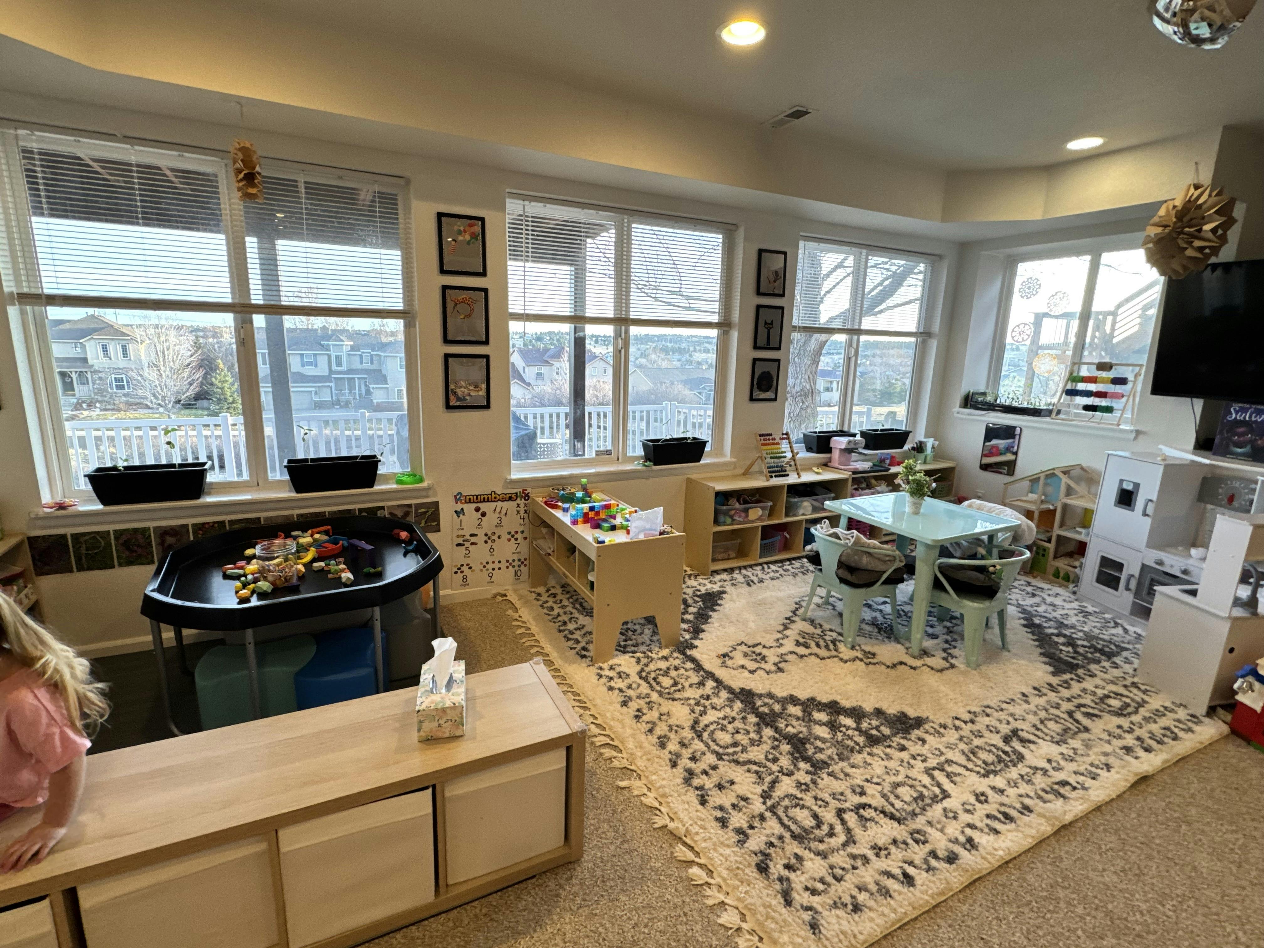 Playroom with windows, small tables, and toys