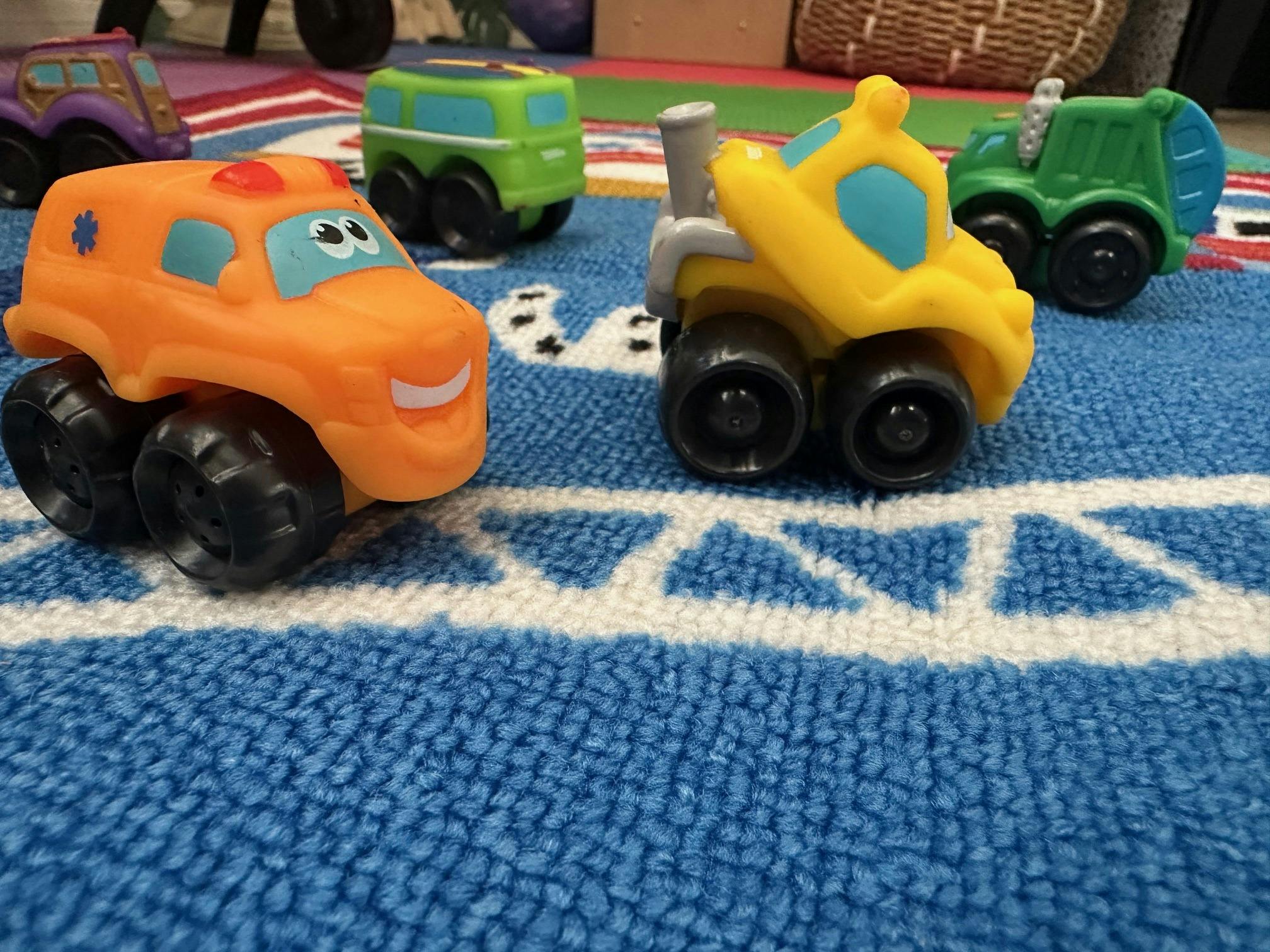 Small plastic toy vehicles on a blue play mat