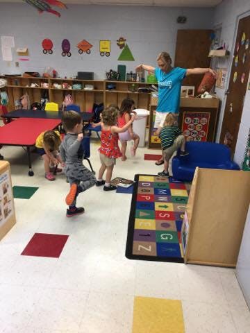Adult and children exercising in a classroom