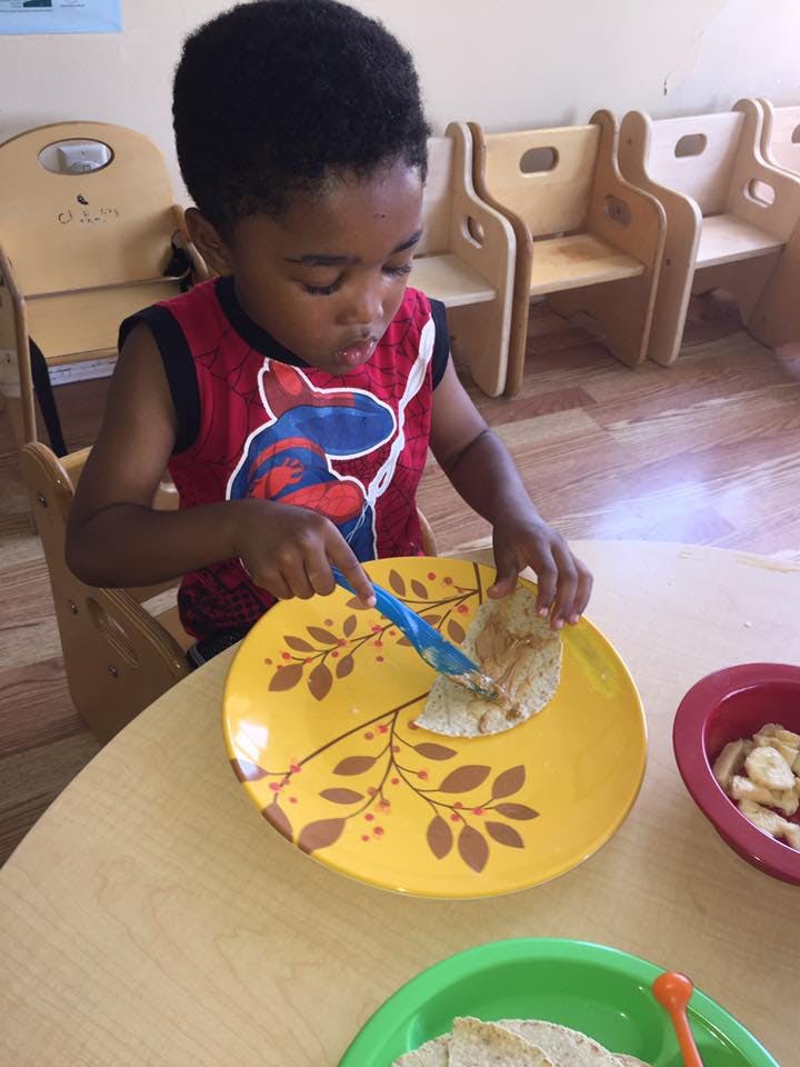 Child spreading food on a flatbread with a spoon