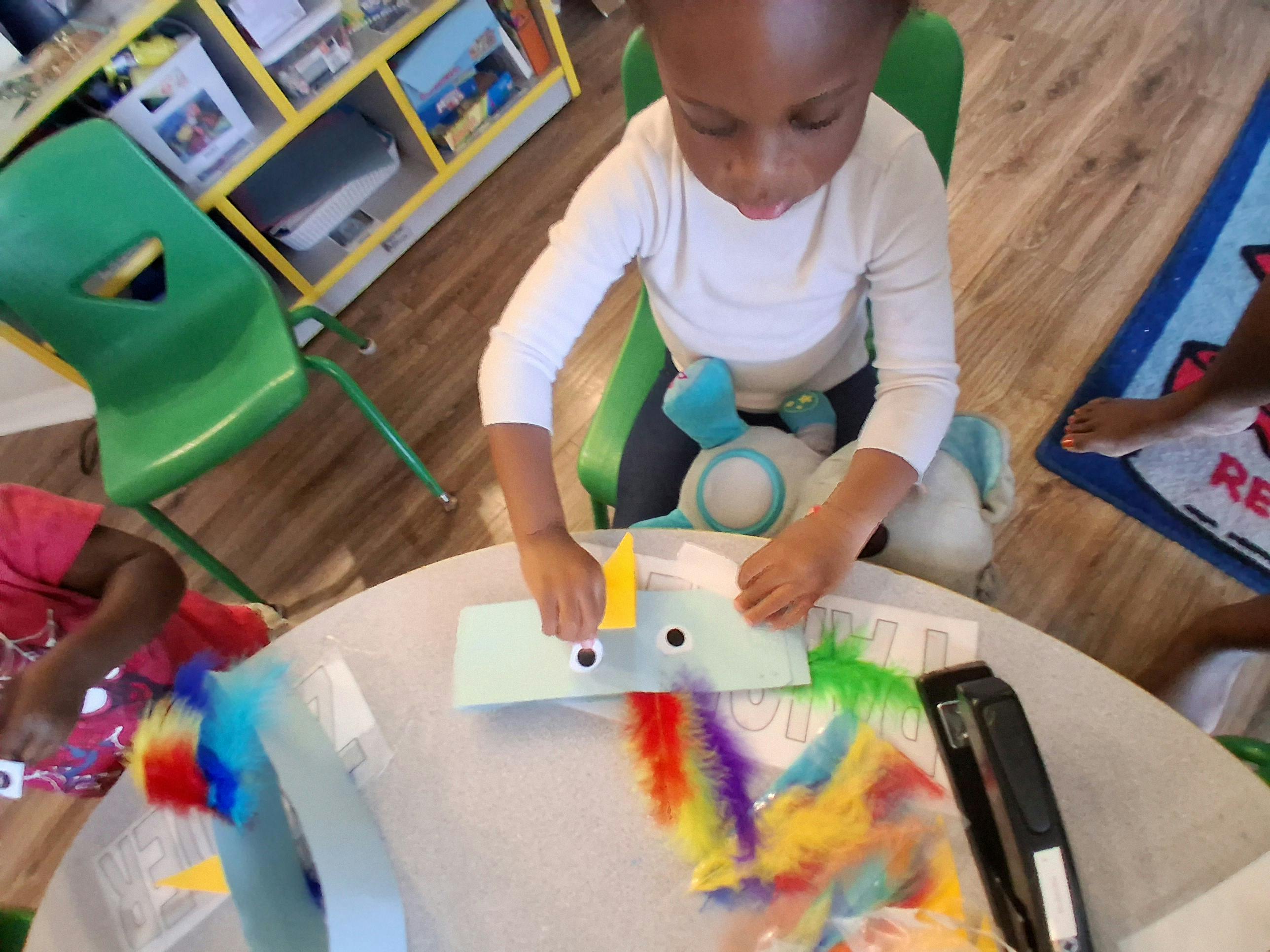 Child crafting with googly eyes and colorful feathers