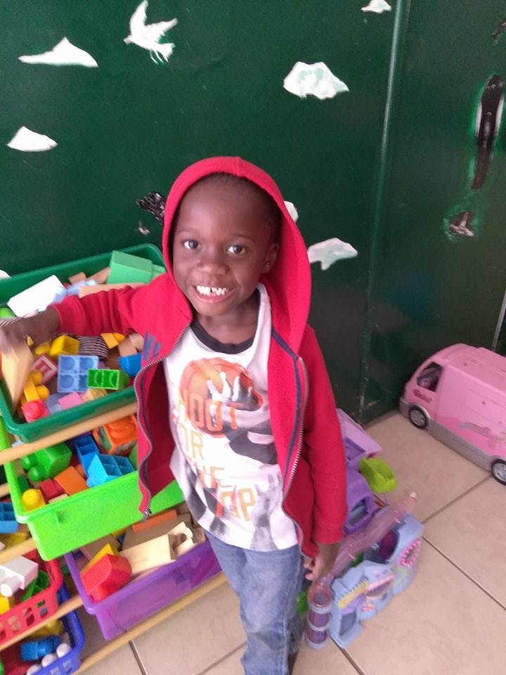 Child in a red hoodie standing next to toy bins