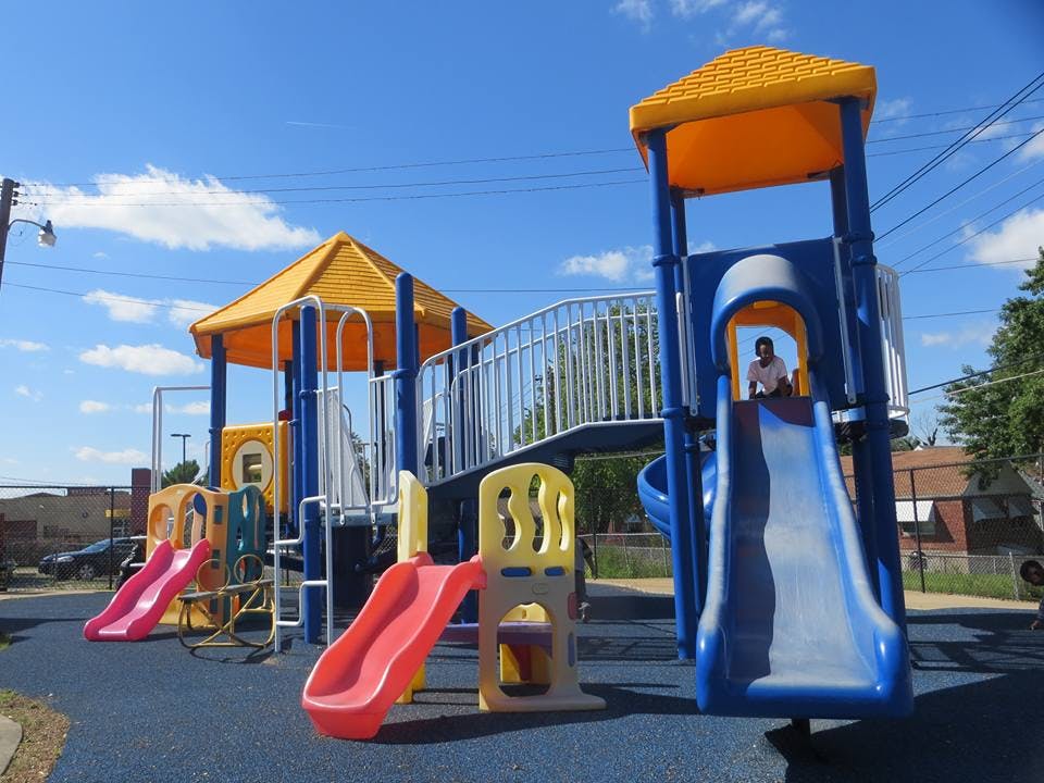 Child at the top of a blue and gray slide on a playground