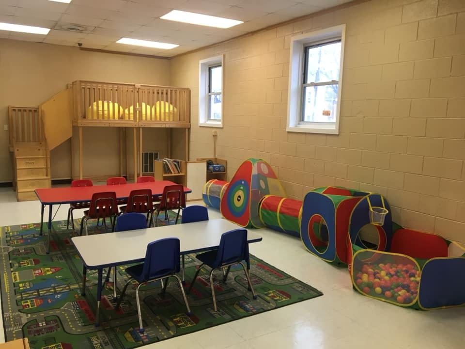 Playroom with tables, chairs, a wooden loft, and colorful play tunnels