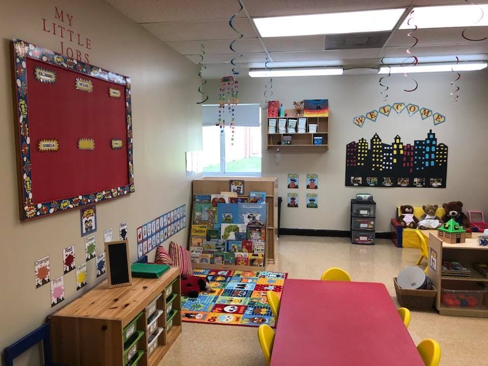 Classroom with a red bulletin board, colorful rug, and small tables
