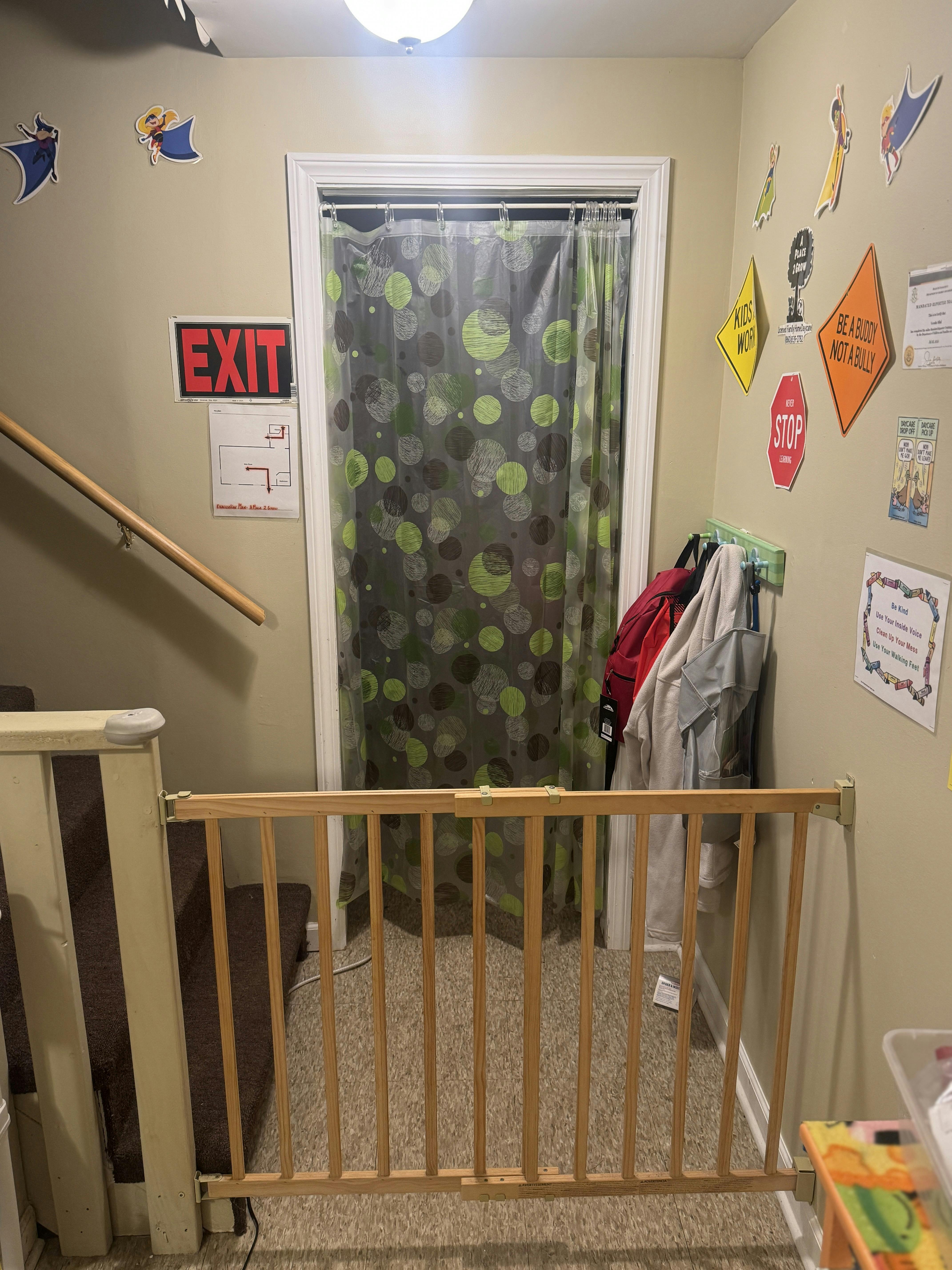 Baby gate at the top of stairs with a shower curtain in a doorway