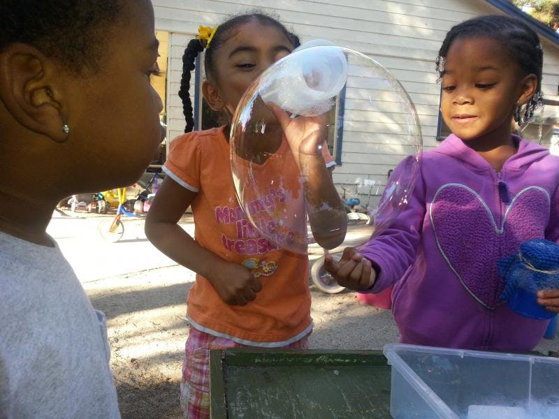 Three children playing with bubbles outdoors