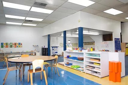 Empty classroom with tables, chairs, and shelves