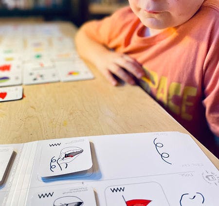 Child looking at a card game on a wooden table