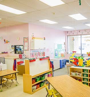 Empty classroom with tables, chairs, and toys
