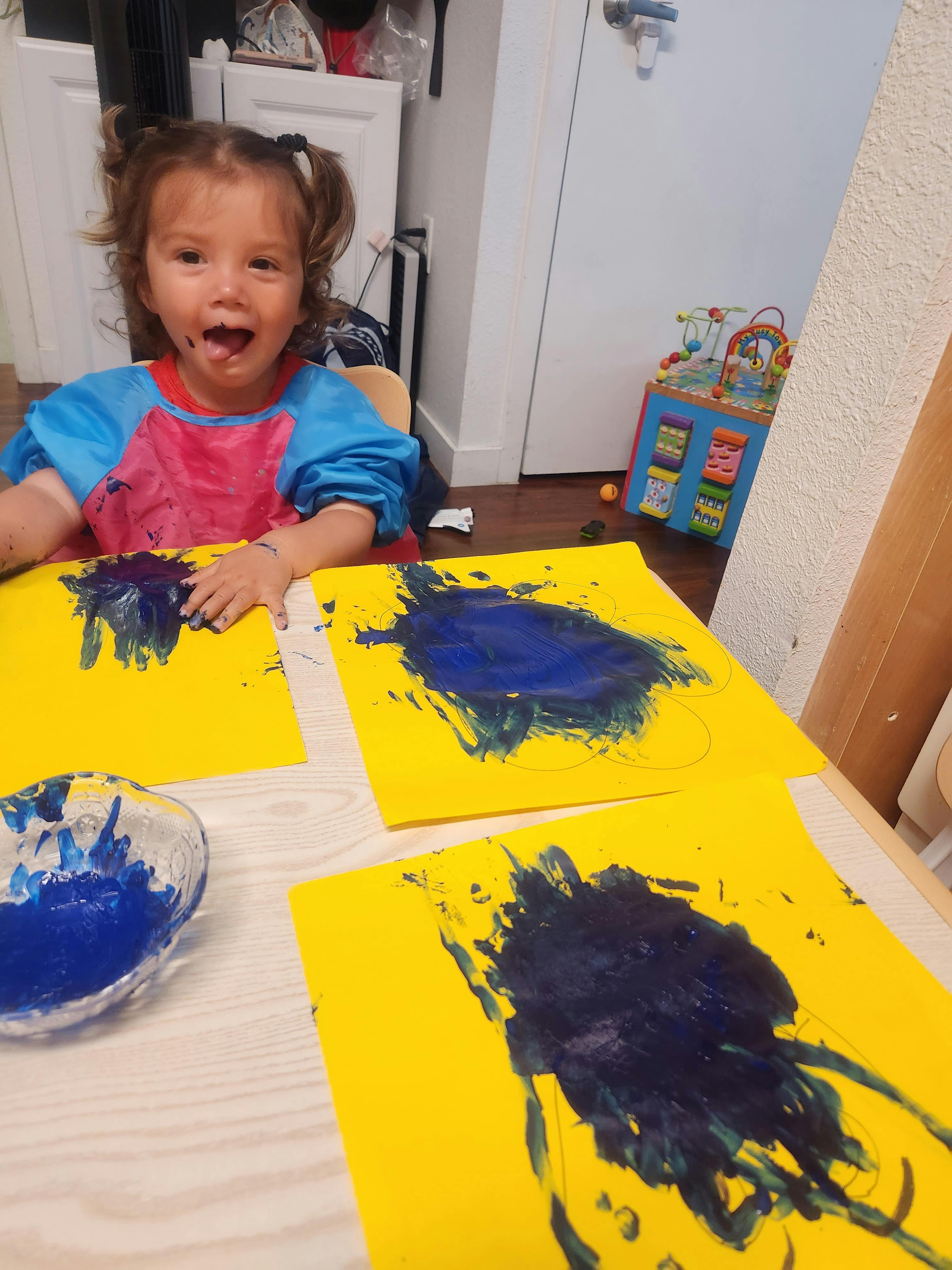 Child finger painting on yellow paper