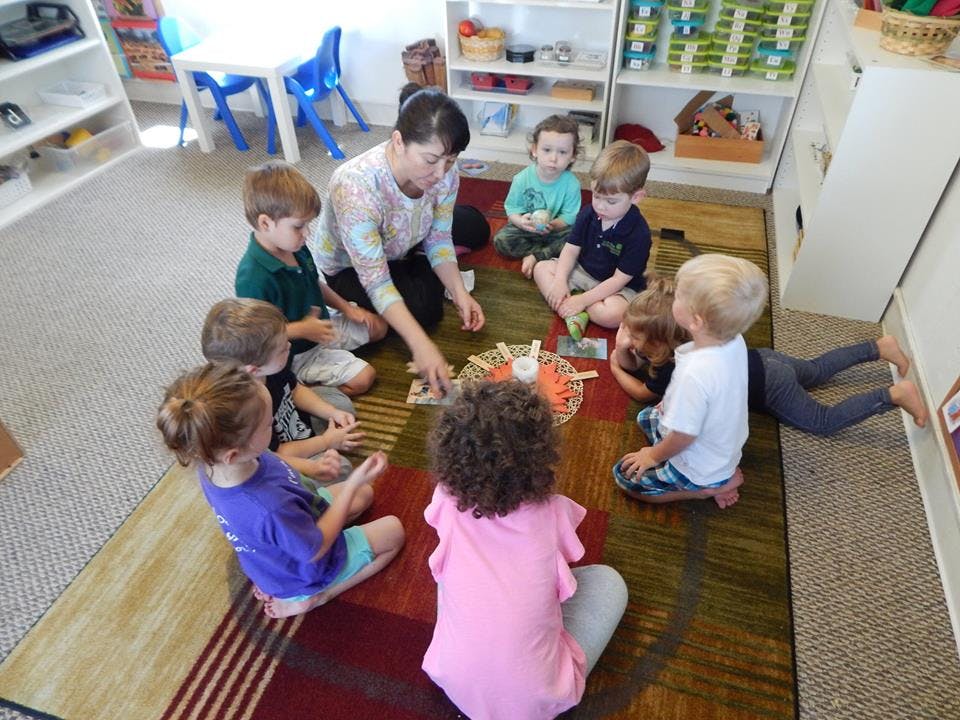 Adult and children sitting in a circle on a rug