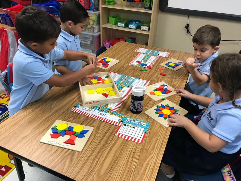 Four children playing with colorful shape puzzles at a table