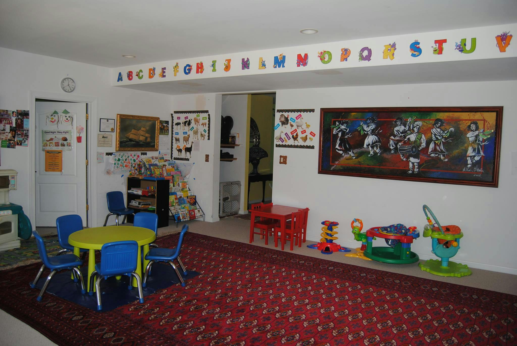 Playroom with small tables and chairs, toys, and alphabet letters on the wall