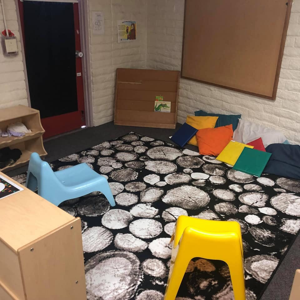 Classroom with a rug, small chairs, and colorful cushions