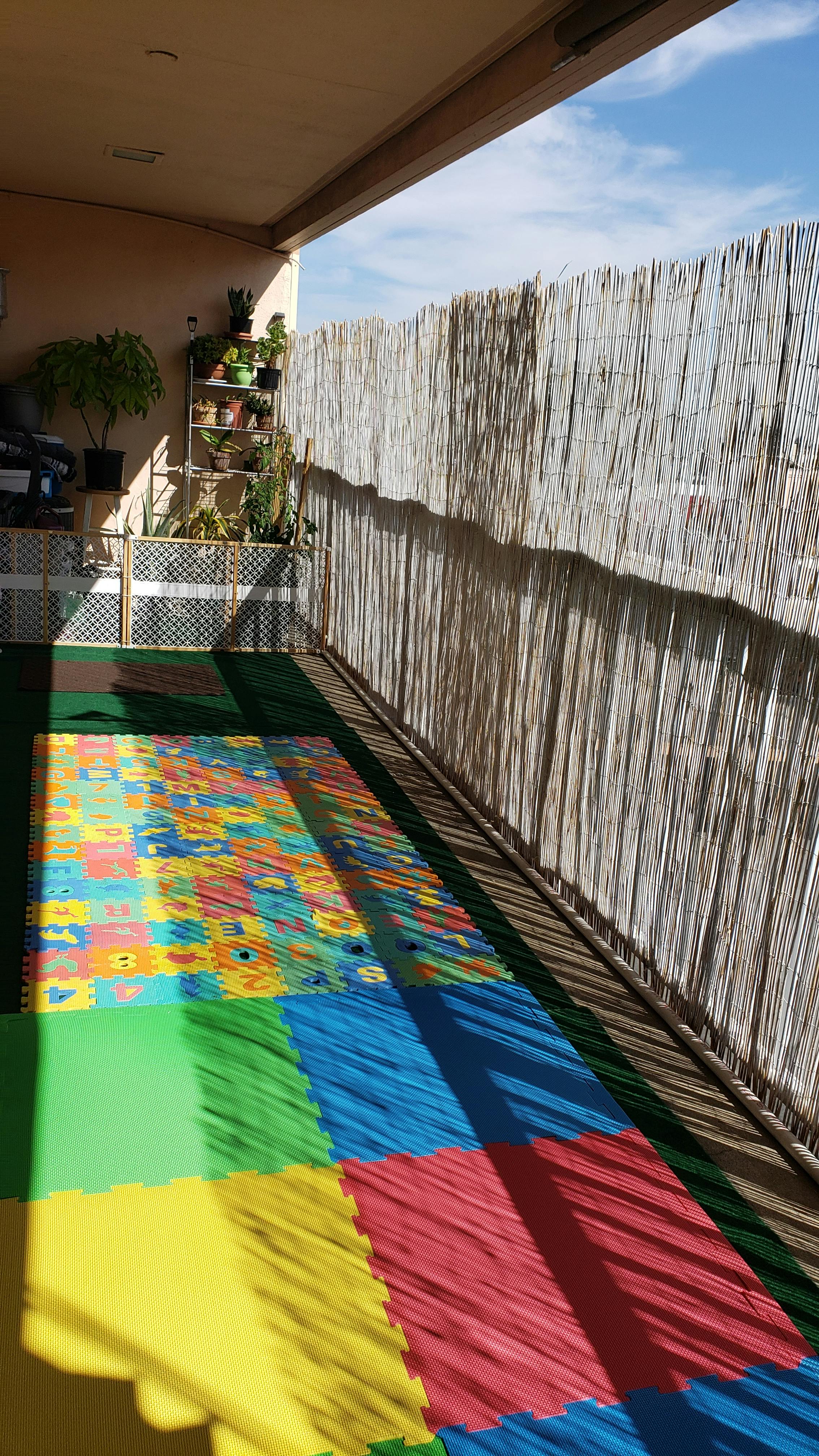 Colorful foam play mats on a patio with a bamboo fence