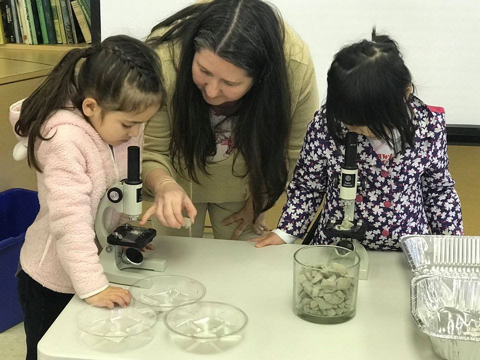 Adult and two children looking at microscopes